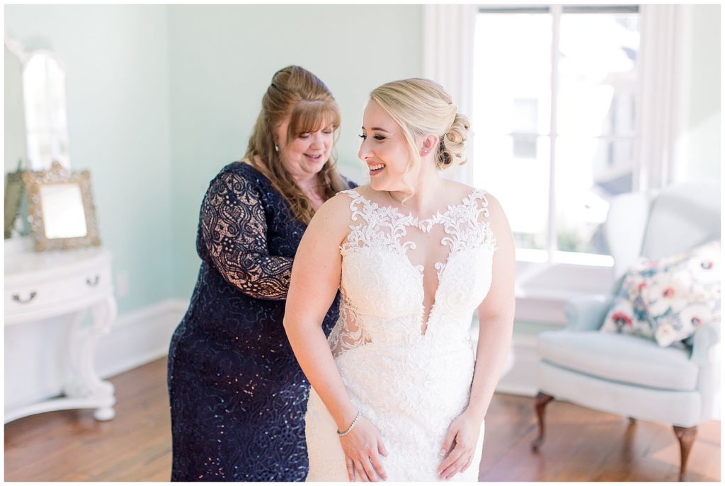 mom of bride zipping up wedding dress