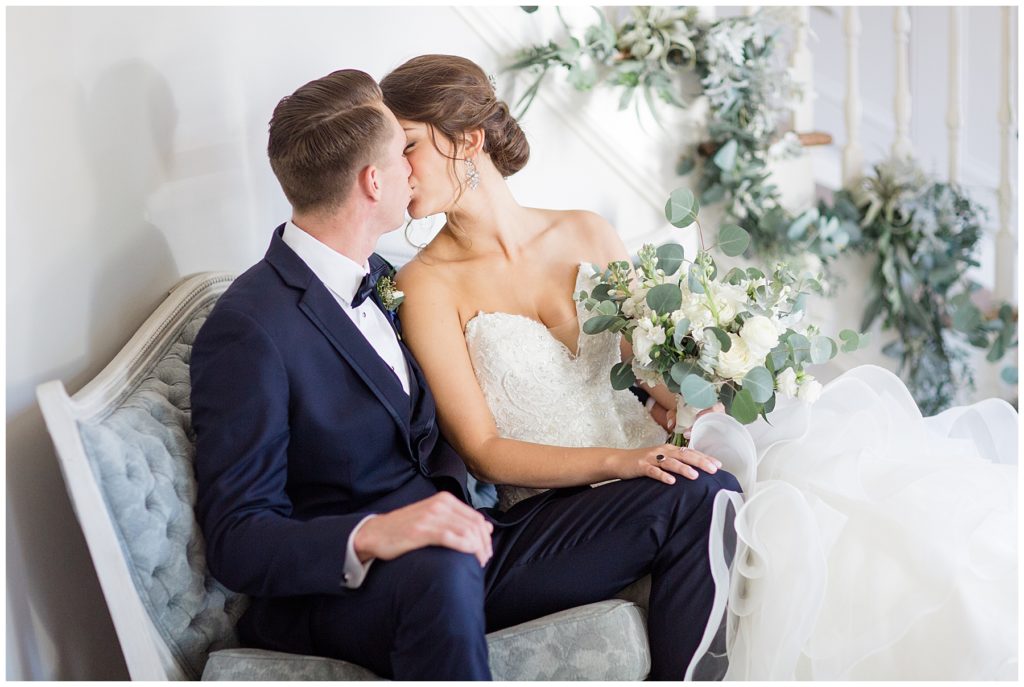 bride and groom kissing and sitting in vintage couch